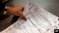 Tax professional and tax preparation firm owner Alicia Utley reaches for tax forms at the start of the tax season rush in her offices in Boulder, Colo., Jan. 14, 2017.