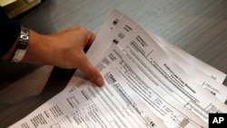 FILE - A tax preparer reaches for hard copies of federal tax forms in Boulder, Colo.
