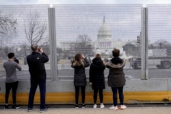 People take photos through the extensive security surrounding the U.S. Capitol in Washington, Friday, Jan. 15, 2021, ahead of the inauguration of President-elect Joe Biden and Vice President-elect Kamala Harris. (AP Photo/Susan Walsh)