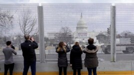 People take photos through the extensive security surrounding the U.S. Capitol in Washington, Friday, Jan. 15, 2021, ahead of the inauguration of President-elect Joe Biden and Vice President-elect Kamala Harris. (AP Photo/Susan Walsh)