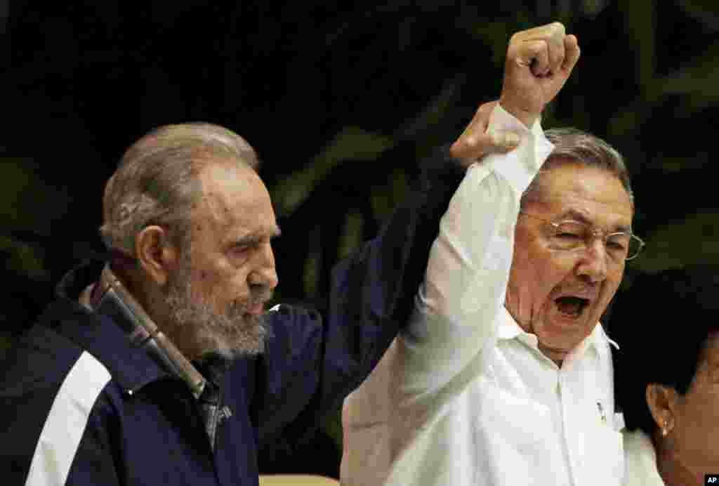 In this April 19, 2011 file photo, Fidel Castro, left, raises his brother's hand, Cuba's President Raul Castro, center, as they sing the anthem of international socialism during the 6th Communist Party Congress in Havana, Cuba.