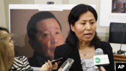 Geng He, the wife of Gao Zhisheng, a political prisoner and China's leading human rights lawyer, speaks in front of her husband's portrait during a news conference, Washington, 18 Jan 2011