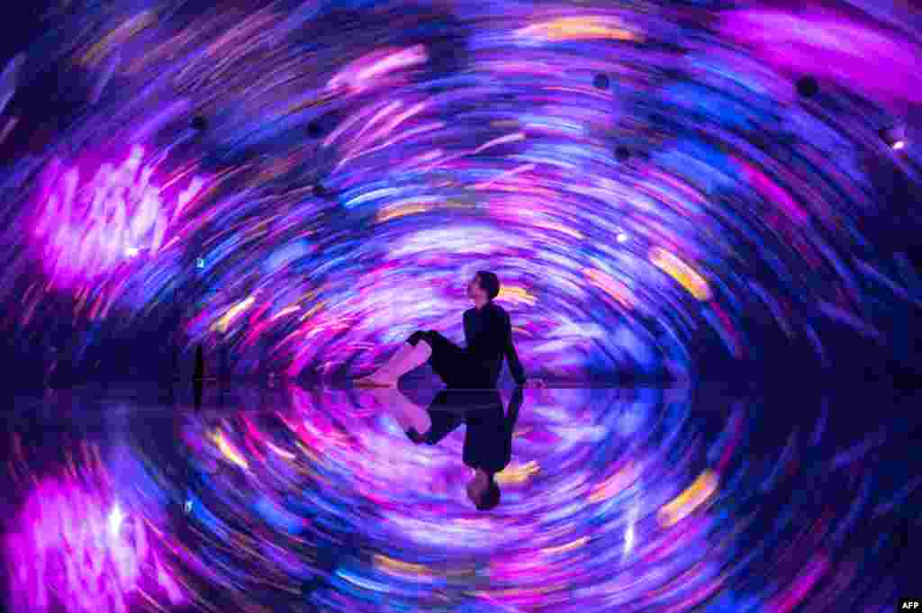 A staff member sits in an interactive digital installation &quot;Floating in the Falling Universe of Flowers&quot; during a media preview at TeamLab Planets in the Toyosu district of Tokyo.