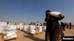 Una desplazada de Mosul carga alimentos en el campo de refugiados de Khazer, al este de Mosul. Noviembre 7 de 2016.