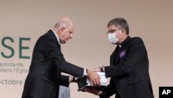 Commission president Jean-Marc Sauve, left, hands copies of the report to Catholic Bishop Eric de Moulins-Beaufort, president of the Bishops' Conference of France, during the publishing of a report by an independant commission into sexual abuse by church 