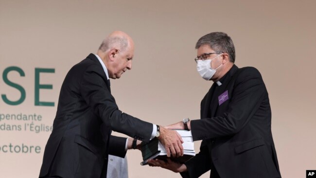 Commission president Jean-Marc Sauve, left, hands copies of the report to Catholic Bishop Eric de Moulins-Beaufort, president of the Bishops' Conference of France, during the publishing of a report by an independant commission into sexual abuse by church