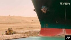 In this photo released by the Suez Canal Authority, a cargo ship, named the Ever Given, sits with its bow stuck into the wall Wednesday, March 24, 2021, after it become wedged across Egypt’s Suez Canal and blocked all traffic in the vital waterway.