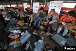FILE - Employees sort packages at a hub of Shentong (STO) Express delivery company in Hefei, Anhui province.