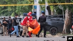 Police officer and rescue workers carry a body bag containing what is believed to be human remains outside a church where an explosion went off in Makassar, South Sulawesi, Indonesia, Sunday, March 28, 2021. 