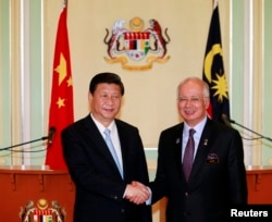 Presiden China Xi Jinping (kiri) dan PM Malaysia Najib Razak berjabat tangan seusai menggelar konferensi pers bersama di kantor PM Malaysia di Putrajaya, dekat Kuala Lumpur (4/10).