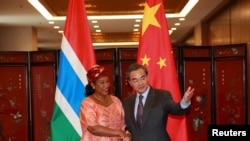 China's Foreign Minister Wang Yi (R) shakes hand with his Gambian counterpart Neneh Macdouall-Gaye during a meeting in Beijing, China, March 17, 2016.