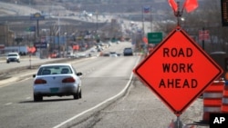 FILE - Construction signs warn drivers on US Route 550 as crews prepare to begin work on the highway in Bernalillo, N.M., Feb. 19, 2015. 