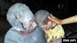 This citizen journalism image taken on April 25, 2013 and provided by Edlib News Network (which has been authenticated) shows a wounded Syrian man holding his injured son after an air raid on the town of Saraqeb in Idlib province.