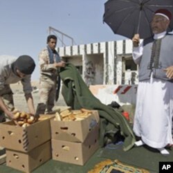 Mohammed Tajouri, 54, a local elder, distributes bread to rebel fighters on the outskirts of Ajdabiya, Libya Thursday, April 14, 2011