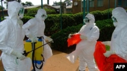 FILE - World Health Organization officials wear protective clothing as they prepare to enter Kagadi Hospital in Kibale District, about 200 kilometers from Kampala.