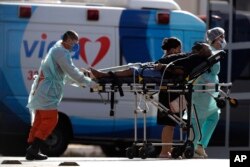 Health workers move a patient suspected of being infected with COVID-19 to the HRAN Hospital, specialized in the care of new coronavirus cases, in Brasilia, Brazil, Monday, Aug. 3, 2020. (AP Photo/Eraldo Peres)