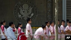  In this May 2012 file photo, Chinese students wait outside the U.S. Embassy for their visa application interviews in Beijing, China.