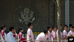 FILE -- In this May 2012 photo, Chinese students wait outside the U.S. Embassy for their visa application interviews in Beijing, China.