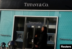 FILE - People walk past a boutique of the luxury jewelry retailer Tiffany & Co. in Beijing, China, Dec. 1, 2016.