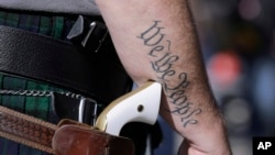 FILE - In this Jan. 26, 2015, file photo, Scott Smith, a supporter of open carry gun laws, wears a pistol as he prepares for a rally in support of open carry gun laws at the Capitol, in Austin, Texas.