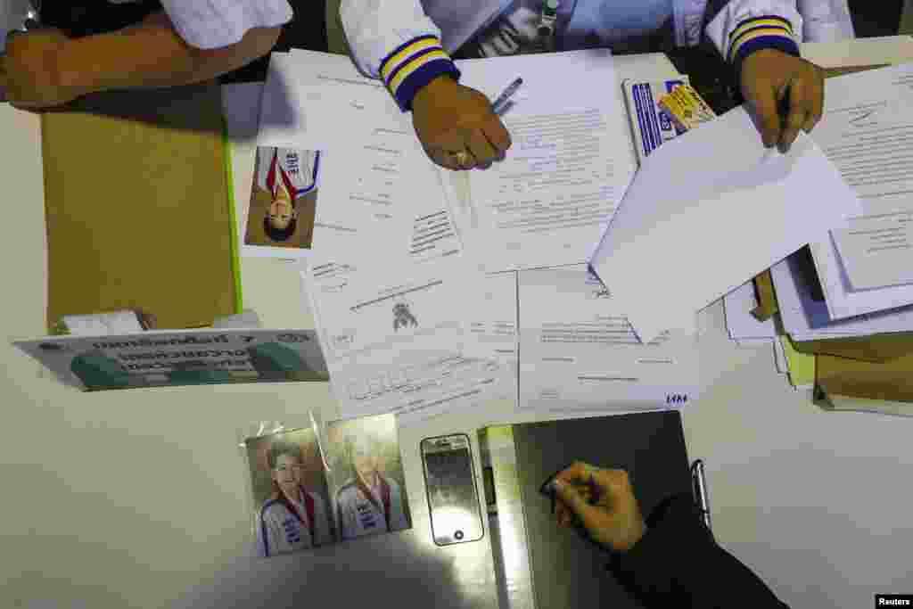 Photographs of Poowanida Kunpalin from the ruling Puea Thai Party are seen as her documents are inspected during a registration of election candidates at a bus terminal centre near the Government complex in Bangkok.