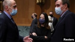 Avril Haines (tengah) bersama Dan Coats (kiri), mantan Direktur Intelijen Nasional AS dan Senator Mark Warner, di Washington DC, 19 Januari 2021. (Joe Raedle/Pool via REUTERS)