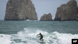 Un surfeador cruza las aguas de Cabo San Lucas en México. La zona fue sacudida este martes por dos fuertes temblores que provocó la evacuación momentánea de turistas.