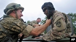 US and Ukrainian servicemen talk during the opening ceremony for the Rapid Trident/Saber Guardian 2015 military exercises in Ukraine, July 20, 2015. (AP Photo/Pavlo Palamarchuk)