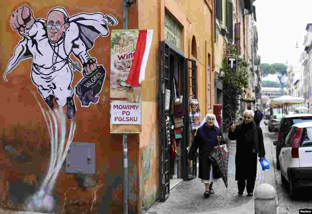 A priest and a nun walk by a large drawing of Pope Francis depicting him as a superhero on a wall near the Vatican.