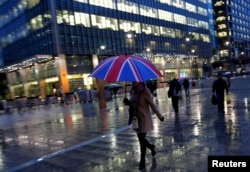 FILE: Workers walk in the rain at the Canary Wharf business district in London, Britain, November 11, 2013.