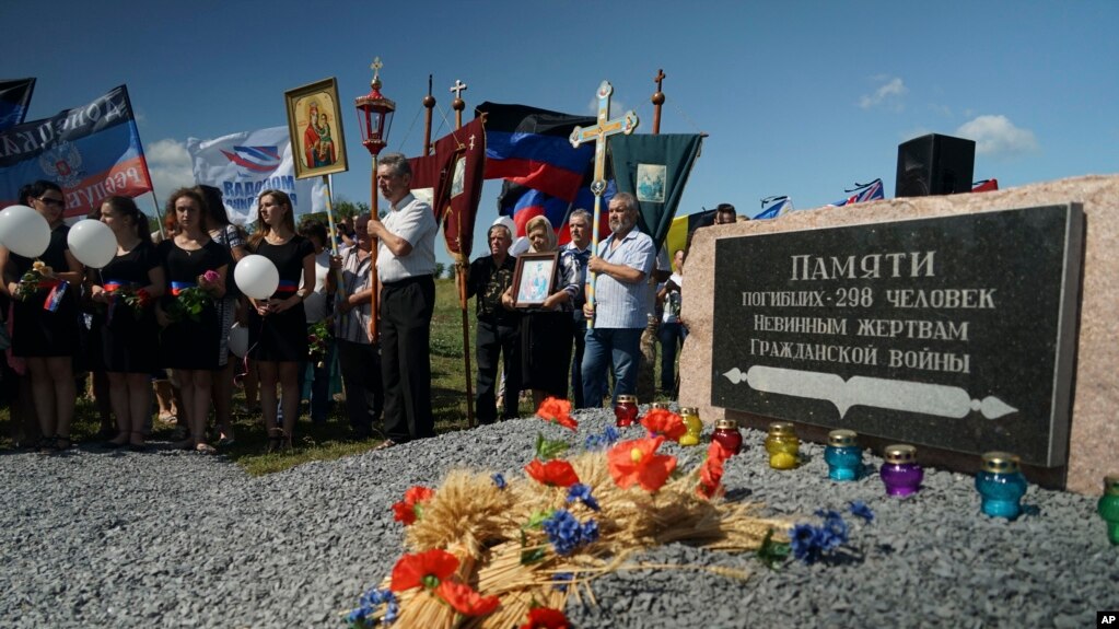 FILE - People stand with Orthodox crosses and icons as they attend a memorial service at the crash site of the Malaysia Airlines Flight 17, near the village of Hrabove, eastern Ukraine, July 17, 2015.