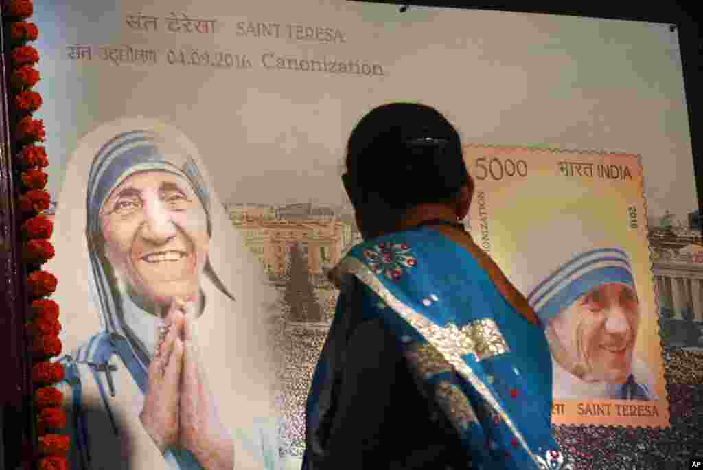 An Indian Christian woman looks at a board displaying a commemorative postage stamp of Mother Teresa during its release function in Mumbai, India, Sept. 4, 2016.
