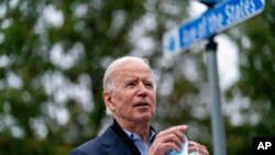 Democratic presidential candidate former Vice President Joe Biden holds his mask as he speaks to members of the media outside a voter service center, Oct. 26, 2020, in Chester, Pa.