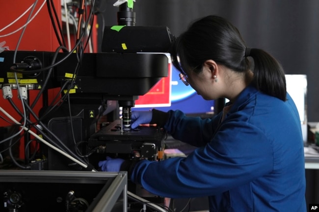 FILE - Naixin Qian, a Columbia physical chemist, demonstrates the placement of a sample for nanoplastics, microscopic plastic pieces, in New York on Monday, Jan. 8, 2024. (AP Photo/Mary Conlon)