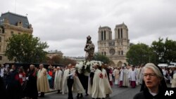 Catholic clergymen and pilgrims take part in an emotional procession with the statue of the Virgin Mary rescued from the April blaze past the fire-ravaged Notre Dame Cathedral to celebrate the Assumption of the Virgin in Paris, Thursday, Aug. 15,…
