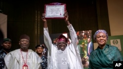 President-Elect Bola Tinubu, displays his certificate accompanied by his wife Oluremi Tinubu and chairman of the Independent National Electoral Commission (INEC) Mahmood Yakubu, at a ceremony in Abuja, March 1, 2023. 