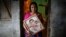 Fatema holds a picture of her son Nurul Karim as she poses for a photograph in front of her house in Savar, April 21, 2014. Fatema lost her son and her daugther Arifa, who were working at the Rana Plaza when it collapsed on April 24, 2013.