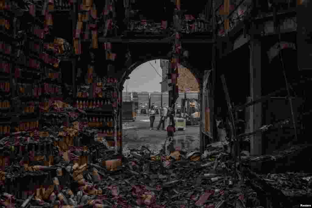 Georg Salzner, president of Castello di Amorosa winery, buries his face in his hand while speaking to Madeleine Reid, the director of hospitality, outside a warehouse containing thousands of wine bottles destroyed by the Glass Fire in Calistoga, California, Sept. 29, 2020.