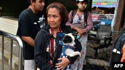 一名缅甸国民为逃离妙瓦底的暴力冲突抱着爱犬越境进入泰国湄索镇的边境检查站。(2024年4月10日)