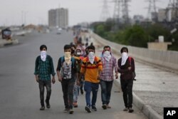 A group of Indian daily wage laborers walk along an expressway hoping to reach their homes, hundreds of kilometers away, as the city comes under lockdown in Ghaziabad, on the outskirts of New Delhi, India, March 26, 2020.