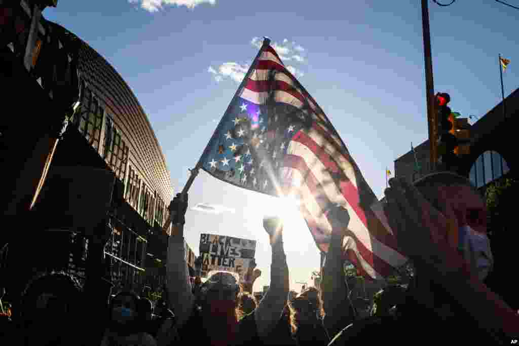 A man holds a U.S. flag upside down, a sign of distress, as protesters march down the street during a solidarity rally for George Floyd, May 31, 2020, in the Brooklyn borough of New York. 