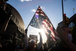 A man holds a U.S. flag upside down, a sign of distress, as protesters march down a street during a solidarity rally for George Floyd, May 31, 2020, in the Brooklyn borough of New York.