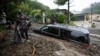 FILE - Residents evacuate past damaged vehicles after storms caused a mudslide, Feb. 5, 2024, in the Beverly Crest area of Los Angeles. The strongest storm of the year brought dangerous debris flows and slides across Southern California on Feb. 14, 2025.