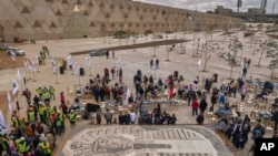 ARCHIVO - Visitantes pasan junto a las copas utilizadas en el mosaico de la máscara del antiguo rey egipcio Tutankamón en el patio del Gran Museo Egipcio cerca de las Grandes Pirámides de Giza, Egipto, el sábado 28 de diciembre de 2019. AP