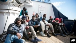 Migrants sit on the deck of the Sea-Eye rescue ship in the Mediterranean Sea, Tuesday, Jan. 8, 2018. 