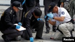 FILE - Members of the police bomb squad investigate the site of a grenade attack on a roof of the National Anti-Corruption Commission office in Nonthaburi province, on the outskirts of Bangkok, March 25, 2014.