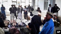 FILE - Afghan men gather around the bodies of several civilians who were killed by Taliban fighters in Ferozkoh, Ghor province, Afghanistan, Oct. 26, 2016. Government forces are now pushing back in Ghor against an insurgent push that resulted in the fall of Taywara on July 23, 2017.