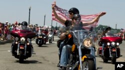 ບັນດາຜູ້ເຂົ້າຮ່ວມໃນການສວນສະໜາມລົດຈັກ ຟ້າສະໜັ່ນ ປະຈຳປີ ຂີ່ລົດຜ່ານຂົວອະນຸສອນ Arlington ໃນລະຫວ່າງການ ແຫ່ສວນສະໜາມກ່ອນວັນ ໄວ້ອາໄລໃນນະຄອນຫຼວງ ວໍຊິງຕັນ. ວັນອາທິດ 24 ພຶດສະພາ, 2015. (AP Photo/Jose Luis Magana)