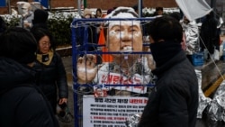 Boneka Presiden Korea Selatan yang dimakzulkan Yoon Suk Yeol terkena salju dalam demo yang menolak kepemimpinannya dekat kediaman resminya di Seoul, Minggu, 25 Januari 2025. (Foto: Tyrone Siu/Reuters)