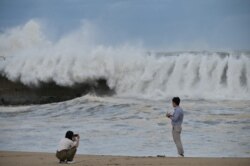 A couple take photos along a sea wall of the waves brought by Typhoon Haishen in the eastern port city of Sokcho on September 7, 2020.